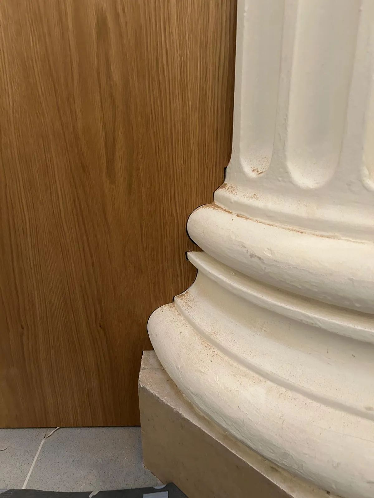 Oak panelling cut to follow the curved mouldings of a column base exactly