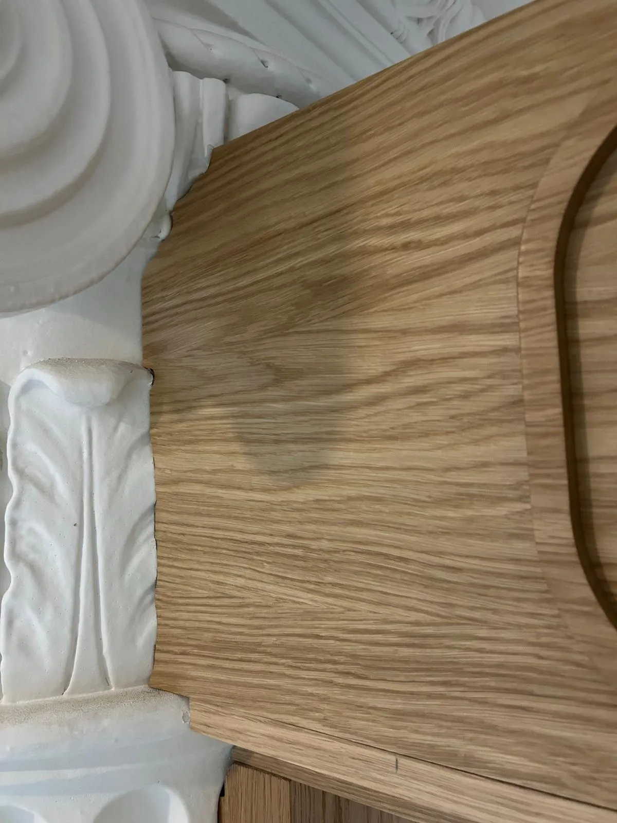 An oak header panel fitted tight to the carving of a column capital