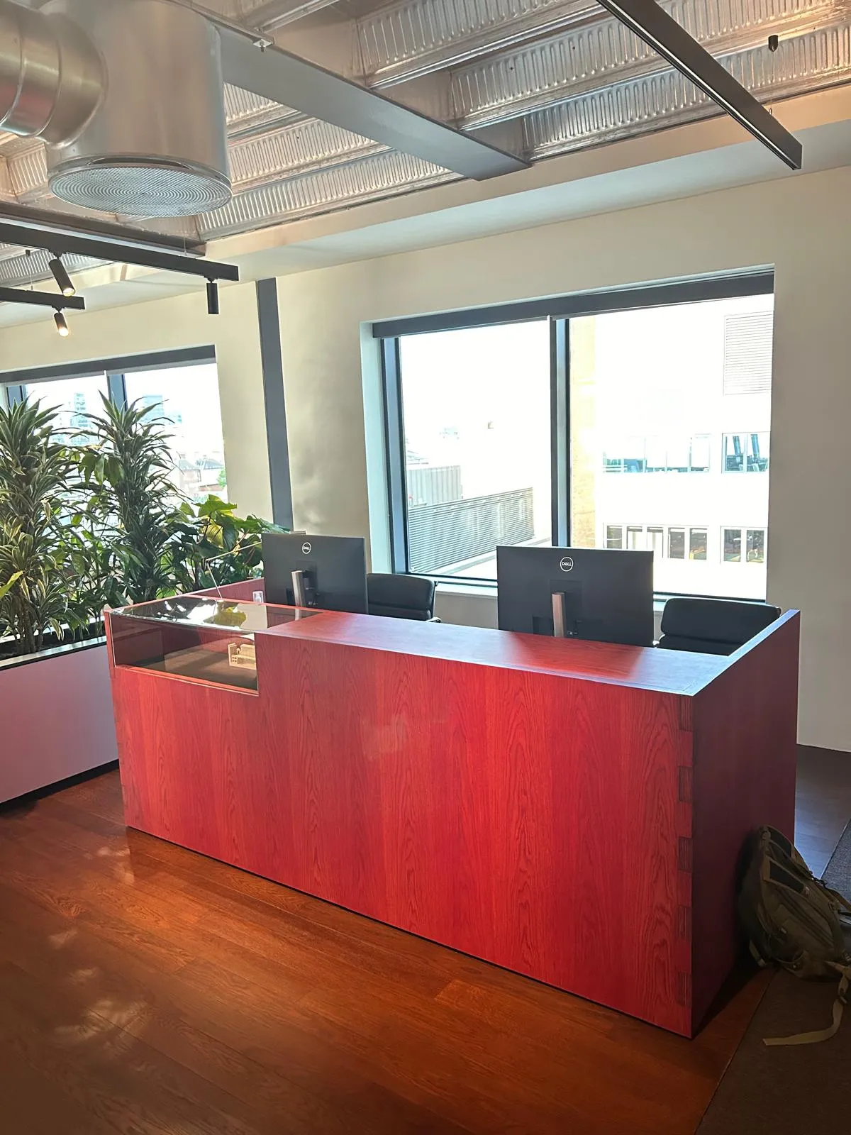 A red veneer reception desk with interlocking corners in an open-plan office