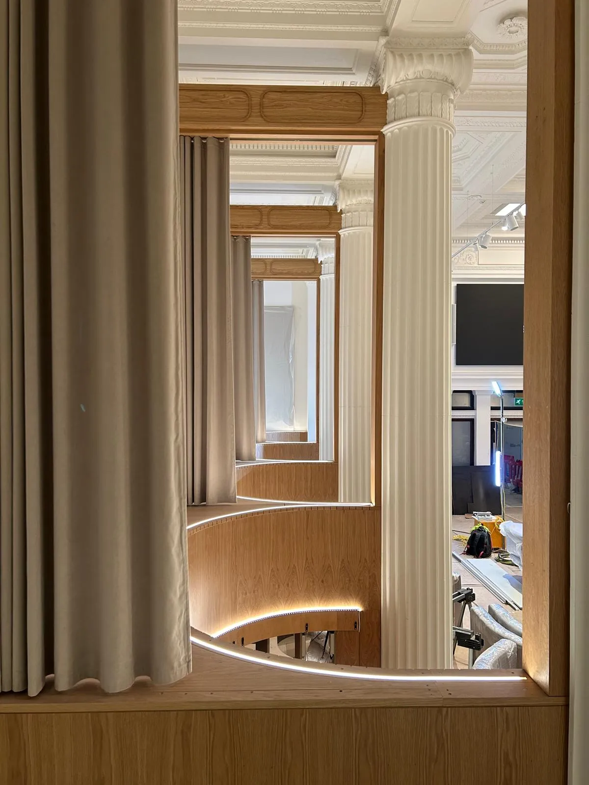 A run of curved booths with lit oak panelling, seen through an oak-lined doorway