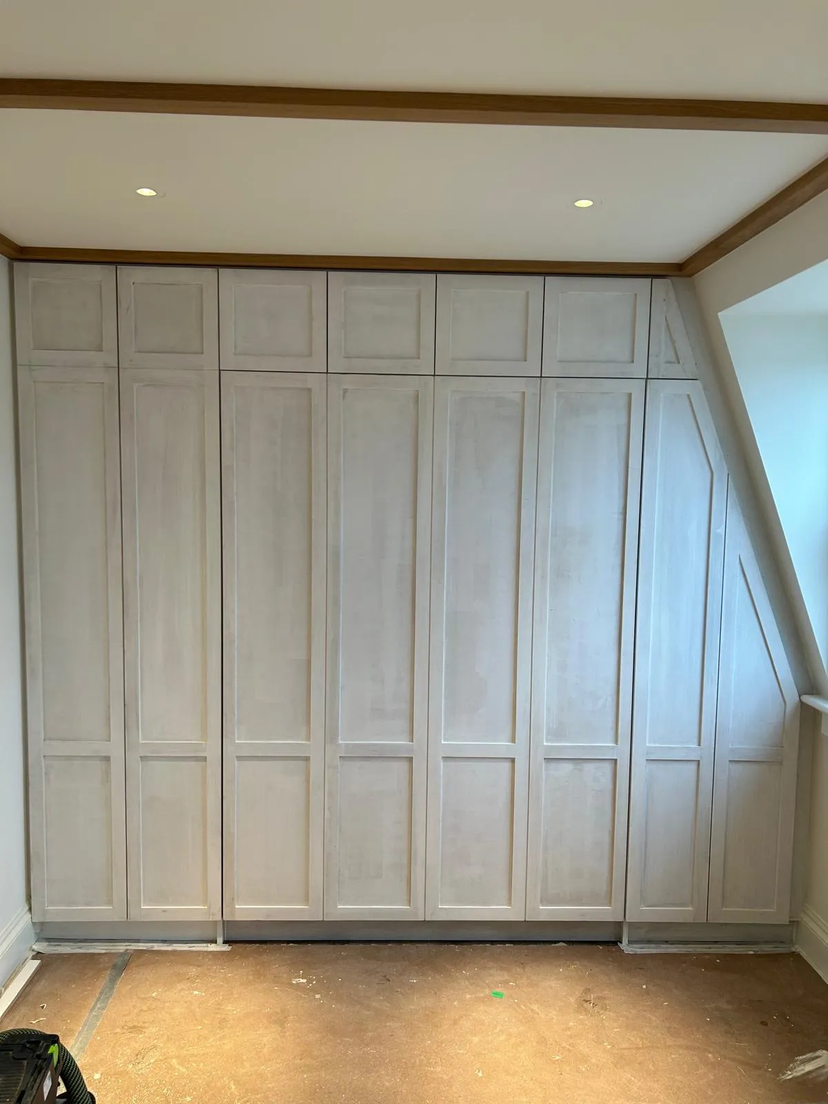 Shaker wardrobes fitted along a loft wall under a sloping ceiling
